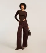 Pantalón wide leg de sarga color marrón oscuro, de talle alto con trabillas para cinturón, cierre de botón y cremallera, con bolsillos delanteros y traseros.