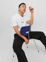 Camiseta blanca de manga corta y cuello redondo con estampado "Originals Studio" en el pecho.