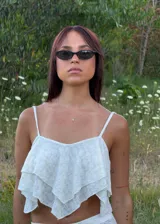 Top corto de tirantes finos, color blanco, con diseño de capas con terminaciones en punta y tela texturada con relieve.