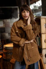 Campera de efecto gamuza color tostado con interior de corderito sintético. Presenta cierre frontal, bolsillos delanteros con solapa, cintura ajustable con cordón y puños con detalle de corderito.