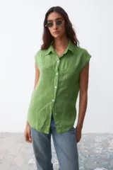 Camisa sin mangas de lino color verde, con cuello clásico, cierre frontal de botones y costura horizontal en el pecho.