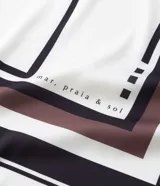 Pañuelo cuadrado de tela satinada con diseño geométrico de rayas y estampado de palmeras en tonos blanco, negro y marrón.