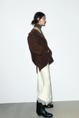 Chaqueta tipo blazer oversize de piel de ante color marrón oscuro, con cuello solapa de muescas, manga larga y bolsillos delanteros con solapa. Cierre frontal con botones.