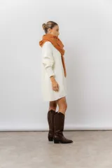 Buzo tipo sweater de punto color blanco, con diseño de trenzas verticales, cuello redondo, mangas largas y tajos laterales. Presenta un corte oversize y largo extendido.