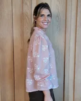 Blusa de algodón color azul, de corte suelto, con mangas largas abullonadas y cuello con volados y escote en V.