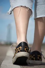 Zapatillas bajas de cuero vacuno con estampado animal print, puntera de gamuza gris, cordones grises y suela de goma.