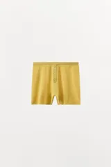 Shorts de tejido de punto color mostaza, de tiro alto con cintura elástica y detalle de botones frontales a tono.
