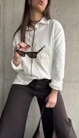 Sweater de hilo color blanco con cuello redondo y diseño de bordados florales en relieve en el frente.