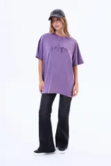 Remera de algodón con efecto lavado, color violeta, de corte oversize y manga corta. Presenta un estampado lineal en el pecho con dibujos de una botella, una fresa, una copa, un florero y una fruta.