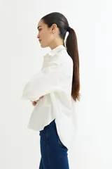 Camisa color beige de corte amplio, con cuello clásico, manga larga y bolsillo en el pecho.