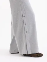 Pantalón de corte recto y silueta holgada, confeccionado en tejido rústico de algodón color verde militar. Presenta cintura con elástico interno y detalles de broches metálicos a presión en los laterales.