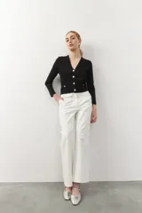 Cárdigan negro corto de tejido de punto, con escote en V, corte ajustado, cierre frontal con botones dorados texturizados y bolsillos simulados con botones dorados.