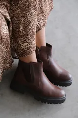 Bota corta de cuero color marrón con suela track dentada y cierre lateral.