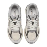 Championes urbanos New Balance modelo 2010, con diseño de paneles en tonos gris, beige y crema. Presentan una combinación de malla técnica y superposiciones de gamuza, con el logo N característico en el lateral y una entresuela robusta con detalles en color bronce.
