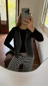 Chaleco negro de ecocuero con tachas doradas.