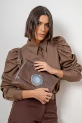 Sobre de cuero color marrón con solapa frontal decorada con una piedra de ágata natural incrustada. Cuenta con cierre trasero y correa ajustable.