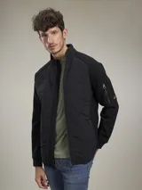 Campera azul marino con cierre frontal, cuello alto y bolsillos laterales con cierre. Tiene un parche rojo con cierre en la manga izquierda y un diseño acolchado en la parte delantera.