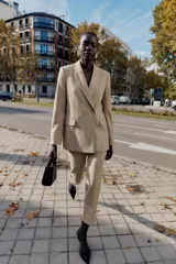 Blazer cruzado de cuello solapa y manga larga, en color beige, con bolsillos con solapa en el delantero y cierre frontal con botones forrados.