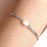 Pulsera de cadena plateada con un dije de perla barroca en el centro.
