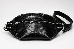 Riñonera de cuero color negro, con múltiples compartimentos con cierre metálico, detalles de tachas en los laterales y correa regulable.