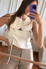 Top blanco de cuero ovino con cuello babero y detalles artesanales en pasamanería.