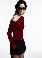 Top de terciopelo color bordó, con diseño asimétrico de un solo hombro, manga larga y detalles fruncidos en el lateral.