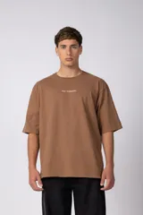 Remera oversize color marrón, de mangas cortas y corte holgado. Cuenta con cuello redondo y una pequeña estampa con texto en el centro del pecho.
