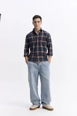 Camisa de manga larga confeccionada en viyela de algodón con diseño de cuadros en tonos azul y verde. Presenta cierre frontal con botones, cuello clásico y bolsillo en el pecho.