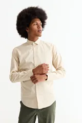 Camisa de manga larga color crema, con cuello camisero y botones frontales. Corte ajustado.