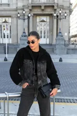 Campera corta de denim negro combinada con corderito sintético negro en cuello y mangas. Presenta cierre frontal con botones metálicos y bolsillos frontales con solapa.