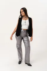 Pantalón plateado de tiro alto confeccionado en gabardina stretch metalizada, con bolsillos y cierre frontal con cremallera y botón.