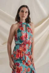 Vestido largo de gasa de seda natural con estampado floral en tonos verde y rojo. Tiene corte en la cintura, falda con volados y tajo delantero.