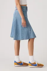Falda midi de denim en tono azul claro, con diseño acampanado y paneles verticales tipo godet.