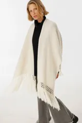 Ruana negra de tejido de punto con flecos y aplique de cuero vacuno con manchas blancas.