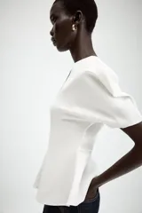 Camiseta negra de cuello redondo con escote en pico, manga corta abullonada y bajo con diseño peplum.