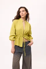 Chaqueta azul con cuello mao, mangas largas abullonadas y lazo en la cintura.