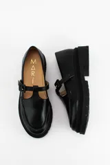 Mocasines estilo Mary Jane de cuero negro con suela track de plataforma. Presentan una tira con hebilla ajustable sobre el empeine y costuras reforzadas en la puntera.