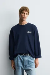 Sudadera boxy fit color azul marino, confeccionada en tejido rib, con cuello redondo y manga larga. Presenta un estampado blanco en el delantero con el texto "The Best Version".