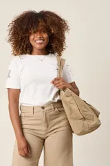 Bolso tote color beige, de tela tipo paracaídas, con doble asa de mano y bolsillo frontal con solapa.