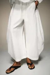 Pantalón blanco de tiro alto con cintura elástica ajustable mediante lazada interior. Presenta bolsillos laterales y un bajo con mucho volumen.