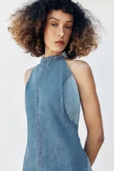Vestido corto de denim con cuello halter, espalda descubierta y diseño de lavado combinado en tonos de azul.