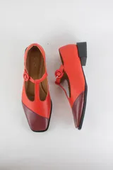 Zapatos de cuero tipo Mary Jane, color rojo con puntera diagonal en tono bordó, cierre de tira en T con hebilla y taco cuadrado bajo de 3 cm.