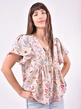 Blusa estampada con cuello en V y lazo ajustable en el escote. Presenta mangas cortas con ligero volumen y un corte holgado con frunces bajo el busto.