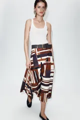 Falda midi de tiro alto en tejido de popelín con diseño evasé. Presenta un estampado geométrico en tonos tierra, crema y negro, e incluye un cinturón a juego con hebilla metálica dorada. Cuenta con cierre lateral mediante cremallera oculta.