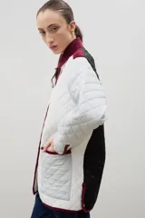 Campera acolchada de corte holgado, color blanco con diseño capitoneado en forma de rombos. Presenta cuello camisero y bordes internos con estampado floral en tonos azul y rojo, cierre frontal con botones a presión y bolsillos laterales.