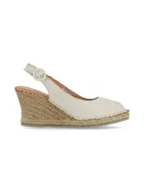 Sandalia de cuero napa color crema, tipo alpargata con cuña de yute, punta cerrada y tira ajustable al tobillo con hebilla.