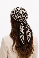 Pañuelo cuadrado de satén con estampado animal print tipo leopardo en tonos beige, negro y marrón, con bordes negros.
