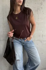 Remera sin mangas color chocolate, con detalle de tachas metálicas doradas en los hombros.