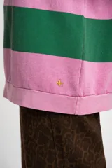 Sweater tipo polo de manga larga con diseño de rayas horizontales anchas en color rosa y gris. Presenta cuello camisero con cierre frontal de botones y puños elásticos.