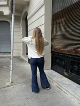 Pantalon oxford de tiro alto, confeccionado en tejido térmico de color azul con efecto desgastado. Presenta un corte ajustado en la parte superior y acampanado desde la rodilla hacia abajo.